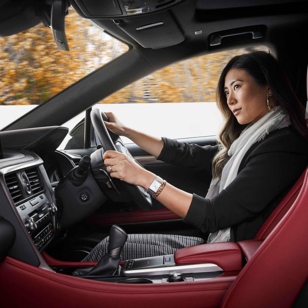 A female in the drivers seat of a Lexus